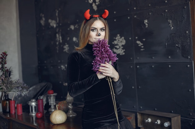 Halloween make-up beautiful woman with blond hairstyle. Model girl in black costume. Halloween theme.