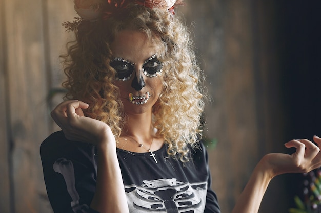 Череп состава хеллоуина красивая женщина со светлой прической. Девушка-модель Санта-Муэрте в черном костюме.