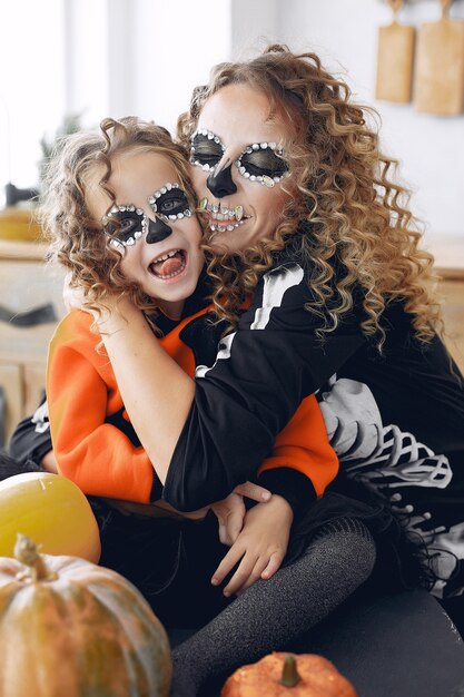 Хэллоуин. Мать и дочь в костюме Хэллоуина в мексиканском стиле. Семья дома с тыквами.