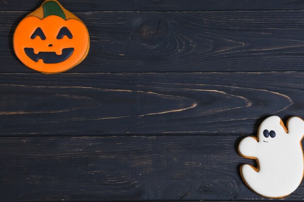 Halloween pumpkin and ghost cookies on wooden desk