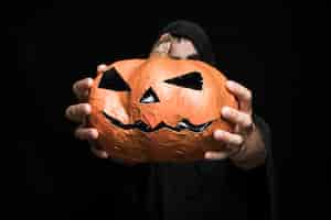 Free photo halloween pumpkin in hands of young man