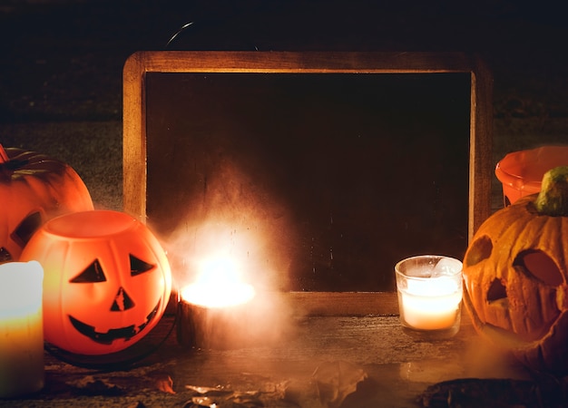 Foto gratuita zucche e candele di halloween con la lavagna