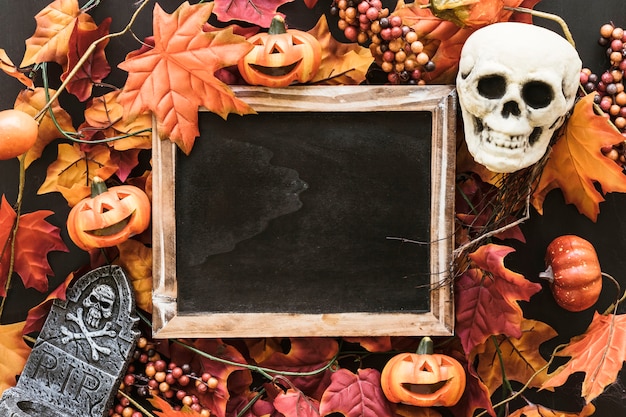 Foto gratuita composizione di ardesia di halloween su foglie d'autunno con il cranio