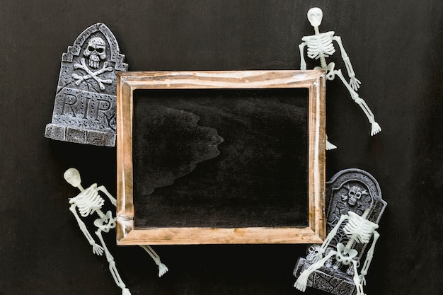 Halloween slate composition with skeletons and tombstones