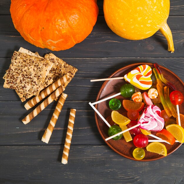 Halloween sweets with pumpkins and cookies on wooden desk