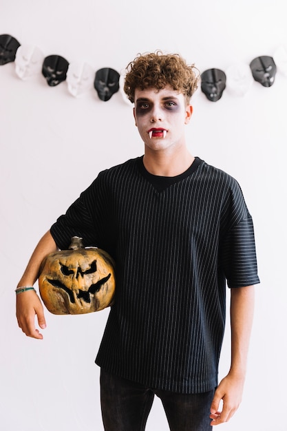 Halloween teenager with vampire fangs and pumpkin