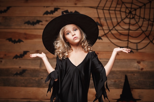 ハロウィーンの魔女の概念-手を脇に持っている小さな白人の魔女の子供のクローズアップショット。