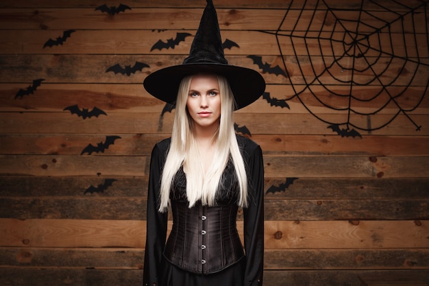 Halloween witch concept  happy halloween sexy witch holding posing over old wooden studio background