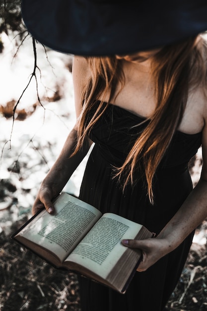 Foto gratuita strega di halloween che tiene libro di incantesimi antico in legno soleggiato