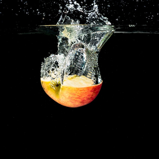 Halved apple with water splash on black background