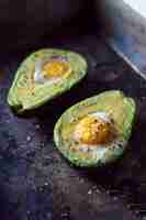 Free photo halved avocado with egg yolk on kitchen worktop