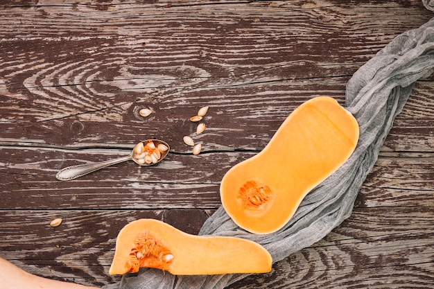 Free photo halved butternut squash and seeds on spoon over the wooden table