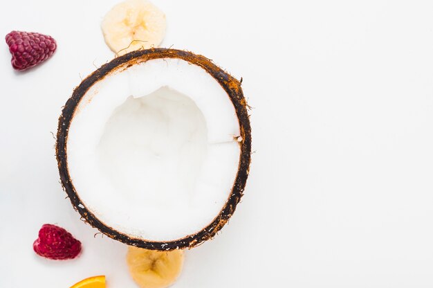 Halved coconut; raspberry; slice of banana on white background