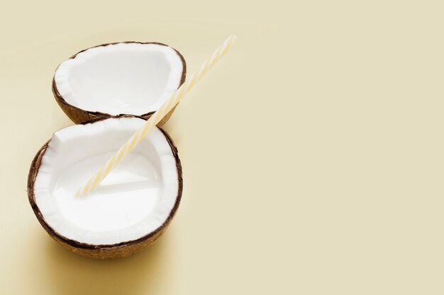 Halved coconut with plastic straw and copy space