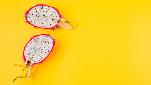 Halved dragon fruit on yellow background