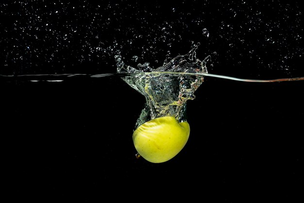 Halved green apple splashing into water