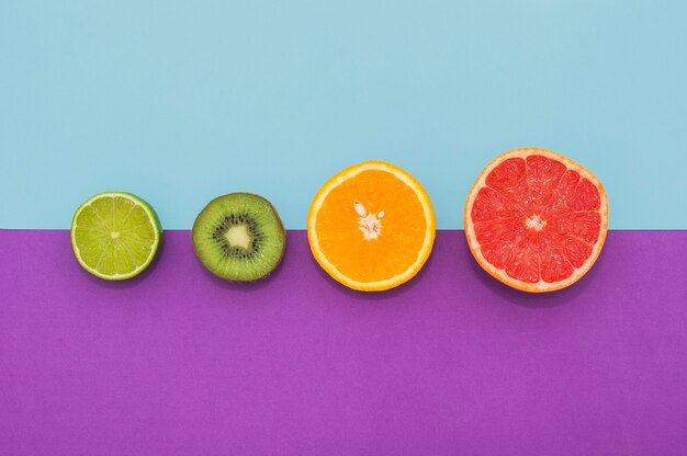 Половинки лимона; киви; оранжевые и виноградные фрукты на двойном фоне