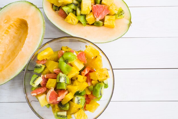 Halved melon with slices of fruits in bowl