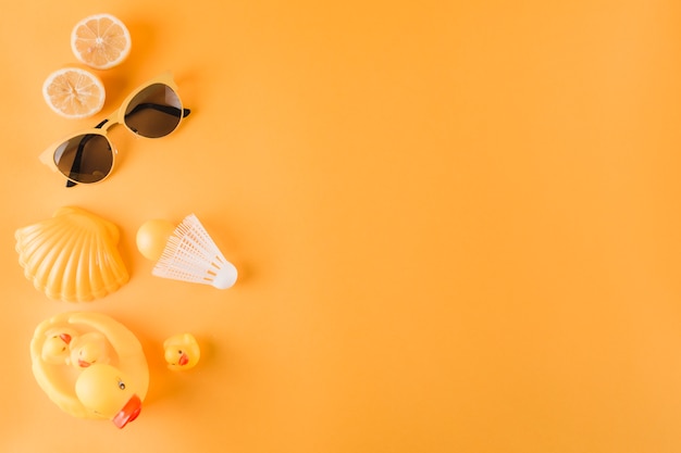 Halved oranges; sunglasses; plastic ball; shuttlecock; scallop and rubber duck on colored background