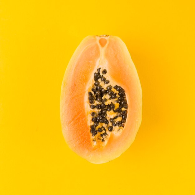 Halved papaya fruit on yellow background