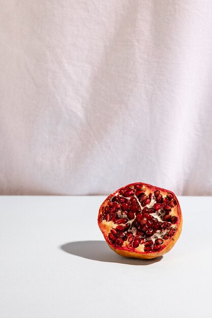 Halved pomegranate on desk in front of white curtain