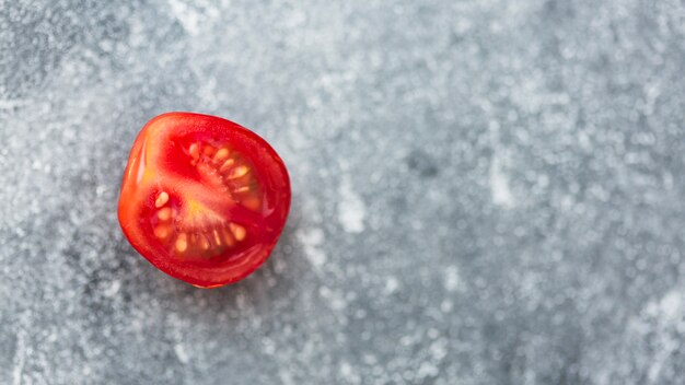 Половинный красный помидор на размытом сером фоне
