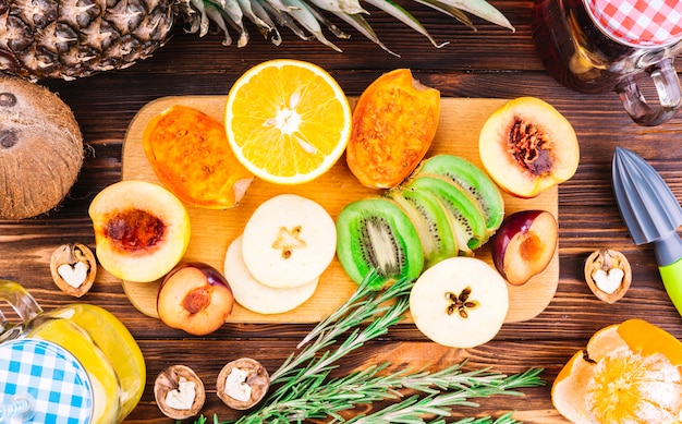 Halved; slices of fresh fruits; walnuts and rosemary on wooden table