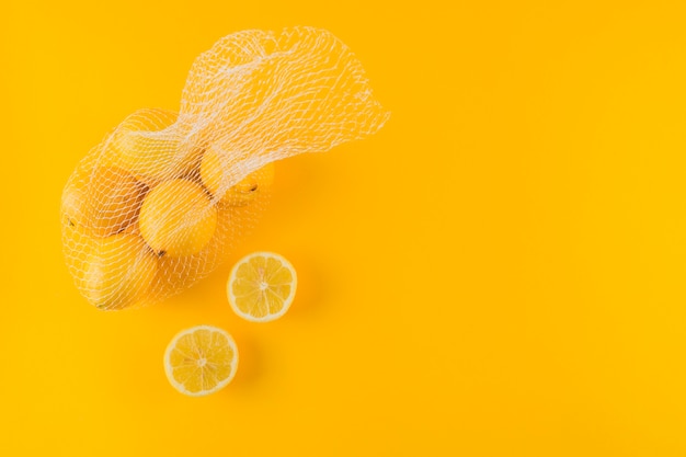 Limoni succosi dimezzati e interi maturi su fondo giallo