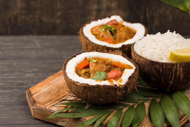 Половинки кокоса, заправленные тушеным мясом и листьями