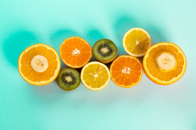 Halves of oranges kiwi and lemons on a blue table