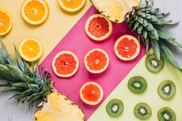 Free photo halves of pineapple near sliced fruits