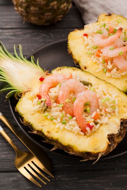 Halves of pineapple with shrimps and golden cutlery