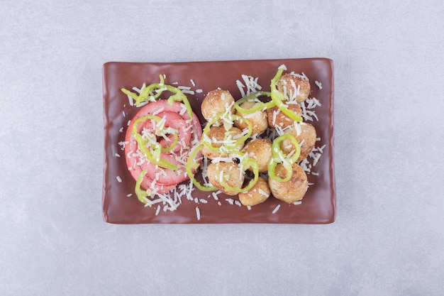 Ham rolls and fried potatoes on dark plate. 