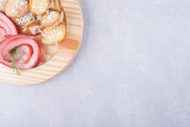 Free photo ham rolls and fried potatoes on wood piece.