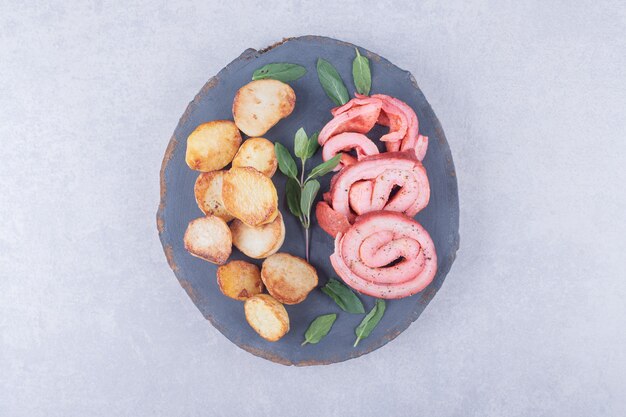 Ham rolls and fried potatoes on wood piece. 