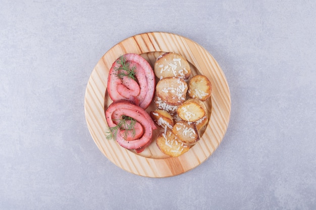 Ham rolls and fried potatoes on wooden plate. 