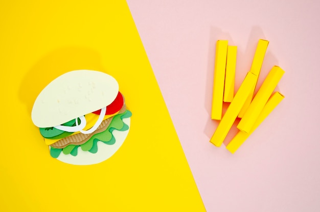 Hamburger and fries replicas on colored background