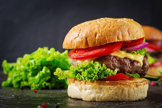 Гамбургер с бургером из говядины и свежими овощами на темной поверхности.