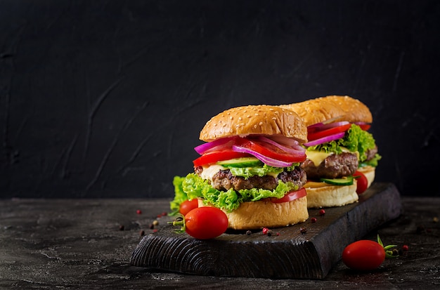 Hamburger with beef meat burger and fresh vegetables on dark surface.