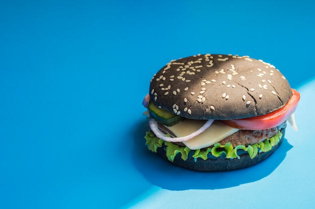 Hamburger with black bun on blue background