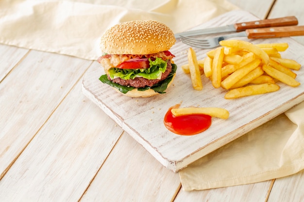 Hamburger with fries and sauce on wooden board