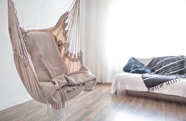 Hammock chair in boho style. Cozy interior. The concept of rest and home comfort. Space for text.