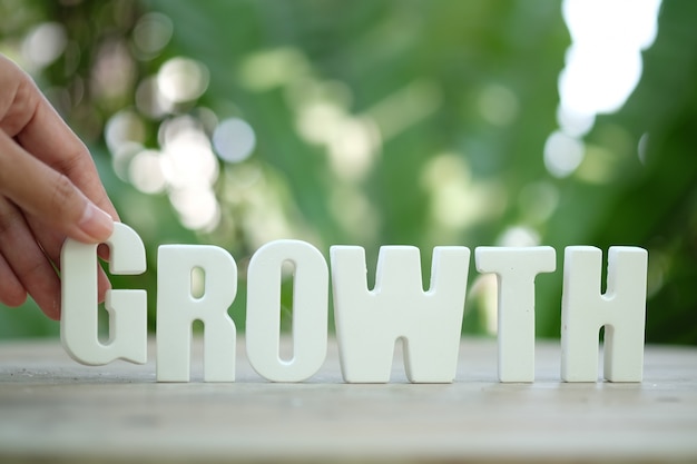 Free photo hand arrange white letters as growth