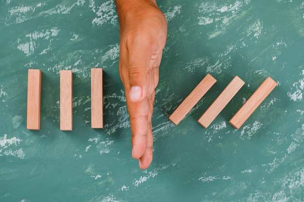 hand as barrier dividing wooden blocks.