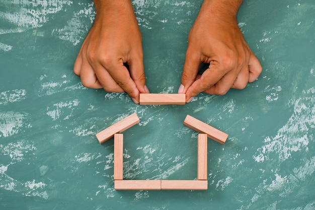 Free photo hand building house with wooden blocks.