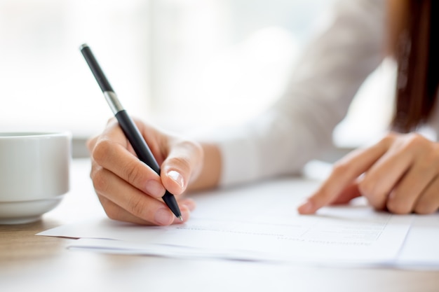 Hand of businesswoman writing on paper in office Free Photo