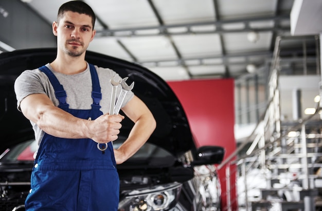 Hand of car mechanic with wrench. Auto repair garage.