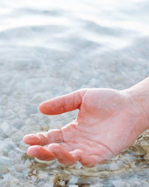 Hand in clear water with sand