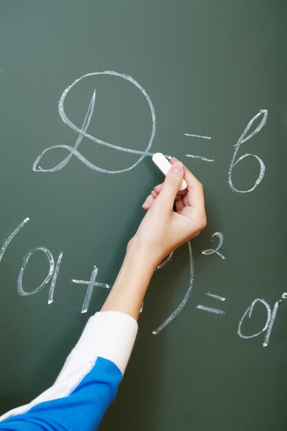 Hand close-up of student writing with chalk on the blackboard