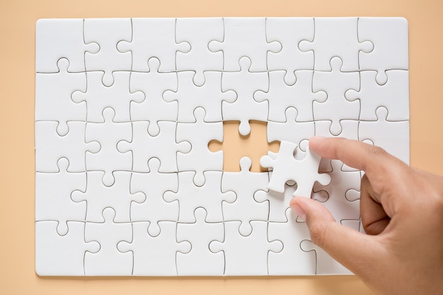 hand connecting puzzle pieces on table background